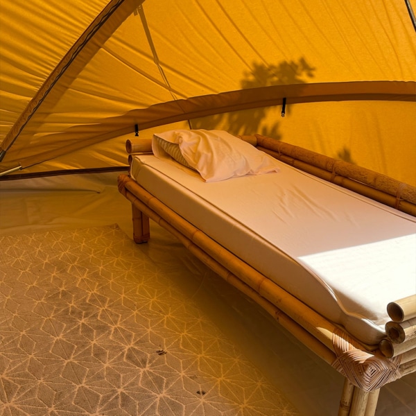 Ecochique glamping tent with spacious living area and darkened bedroom.