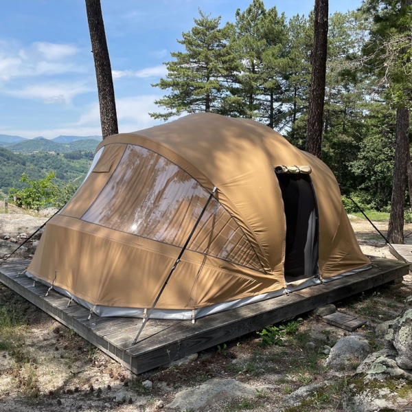 Ecochique glamping tent with spacious living area and darkened bedroom.